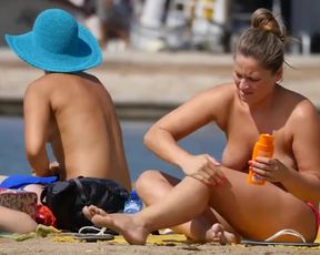 Topless chicks lotion up on the beach